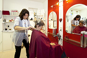 Mitarbeiterin schneidet Seniorin die Haare