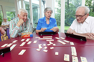 Drei Senioren spielen Rummikub